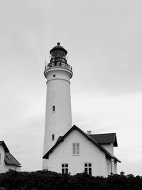 Low angle view of lighthouse by building against sky