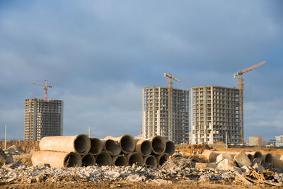 Low angle view of crane by building against sky