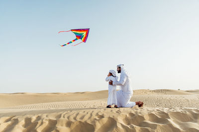 Men standing on desert against clear sky