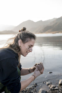 Woman putting mud on hands and face while enjoying outdoors in nature.