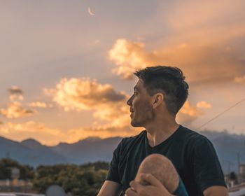 Man looking away against sky during sunset