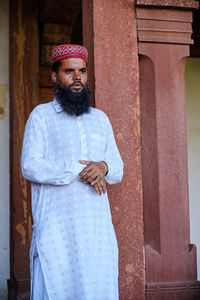 Portrait of young man standing against wall