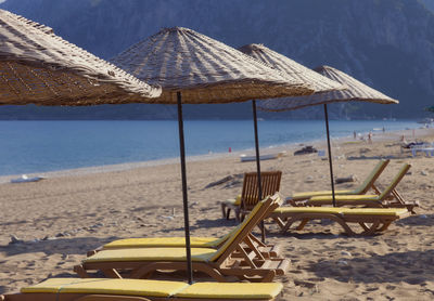 Deck chairs on beach by sea against sky