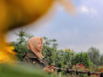 Woman looking away against trees