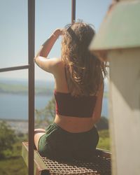 Rear view of woman standing by sea against sky