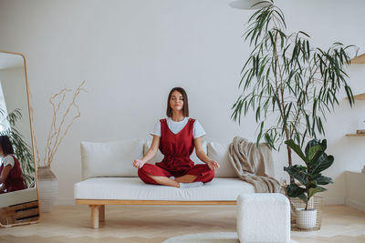 Young woman doing yoga at home. sitting in the lotus position