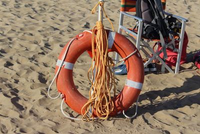 High angle view of life belt and ropes by chair at sandy beach