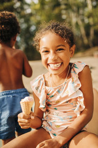 Portrait of happy girl holding ice cream on sunny day