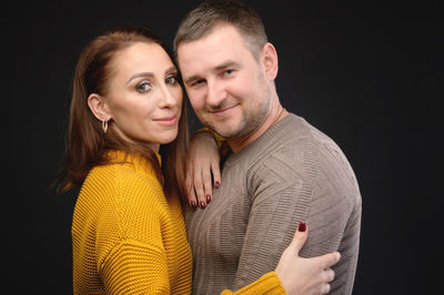 Portrait of young couple against black background