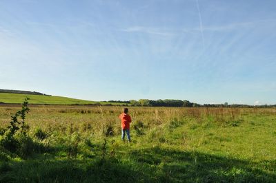 Boy standing on field against sky