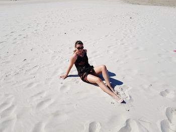 High angle view of woman sitting on sand at beach