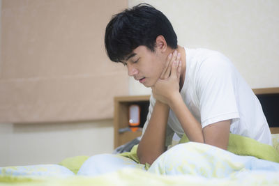 Rear view of man sitting on bed