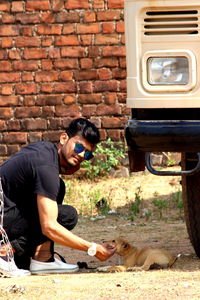 Side view of man touching dog on field