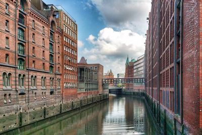 Bridge over canal amidst buildings in city against sky