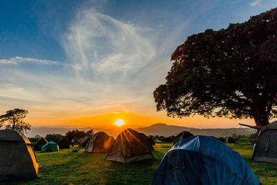 Tent on field against sky during sunset