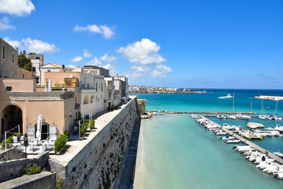 Buildings by sea against blue sky