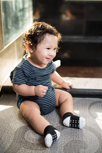 Cute boy sitting on floor at home