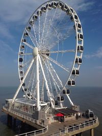 Ferris wheel in sea against sky