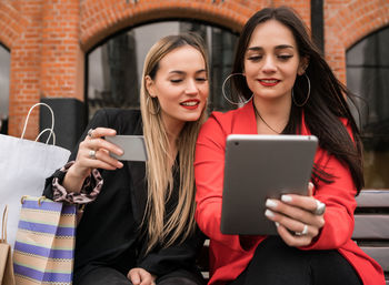 Smiling young woman using mobile phone in laptop