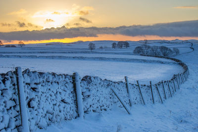 Scenic view of frozen landscape against sky during sunset