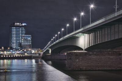 Illuminated bridge over river against sky at night