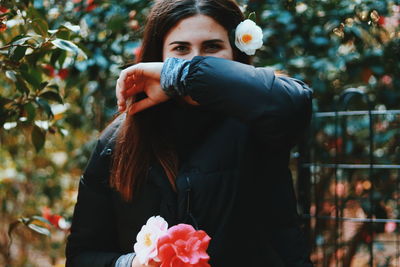 Portrait of woman wearing flower against tree