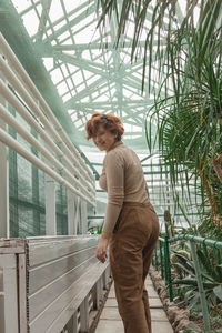 A beautiful plus size girl runs across greenhouse among the green plants. 