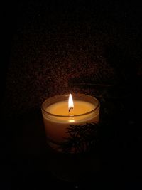 Close-up of lit tea light candle in darkroom