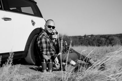 Man sitting on field against sky