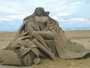 Statue of sand on beach against sky