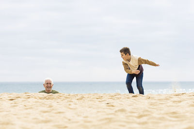 Funny boy and his grandfather on the beach