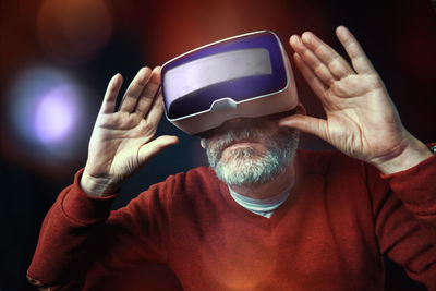 Senior man using virtual reality headset against colored background