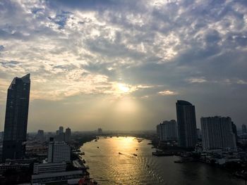 City at waterfront against cloudy sky