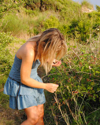 Side view of young blonde woman picking blackbarries