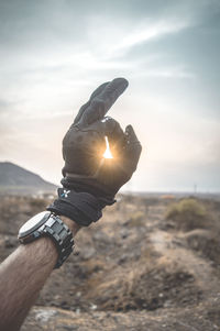 Midsection of person hand on land against sky