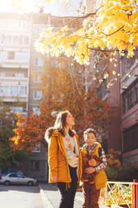 Sibling standing on road in city during autumn