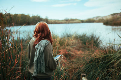 Rear view of woman looking at lake against sky