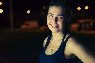 Smiling young woman standing outdoors at night