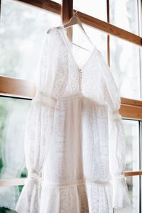 Close-up of white dress hanging by window at home