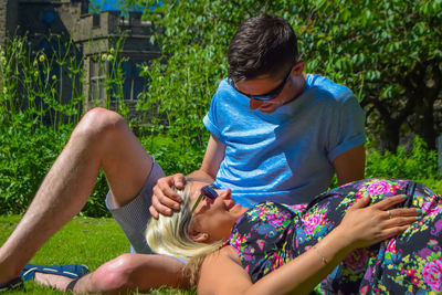 Pregnant woman lying on boyfriend lap at park