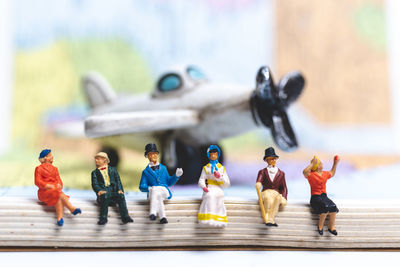 High angle view of figurines on book against toy airplane on table