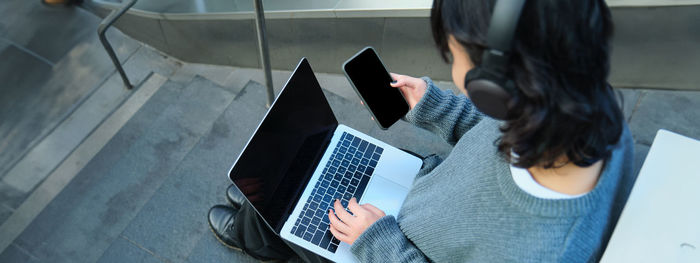 Rear view of woman using laptop at home