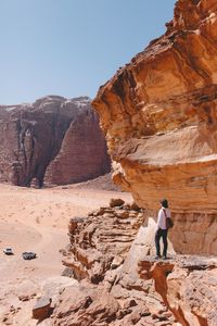 Man on rock formation against clear sky