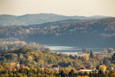 Trees and houses by mountains against sky