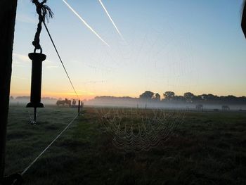 Scenic view of grassy field against sky at sunset