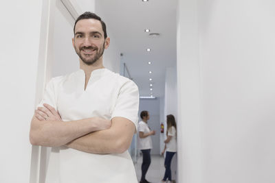 Portrait of smiling doctor standing in hospital corridor
