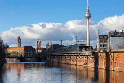 Bridge over river in city against sky