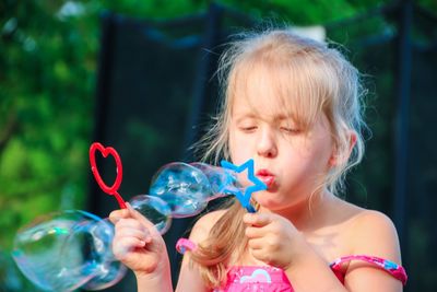 Cute girl blowing bubbles from wand