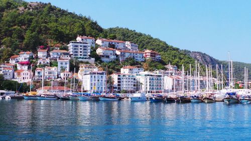 Boats moored on sea by town against clear sky