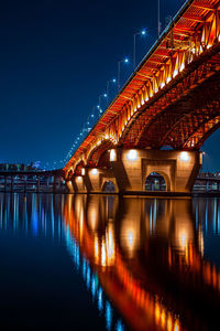 Illuminated bridge over river at night